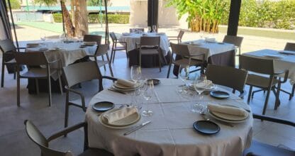 Terraza exterior con mesas redondas y vajilla elegante del Restaurante Malvasía en Playa Honda