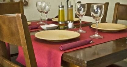 Mesa interior con mantel rojo, platos y copas de vino en Restaurante Piccolo & Tandoori, La Manga del Mar Menor