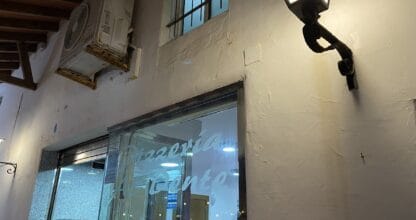 Entrada nocturna de Pizzería Al Dente en La Manga del Mar Menor con puerta de cristal y farol de pared encendido