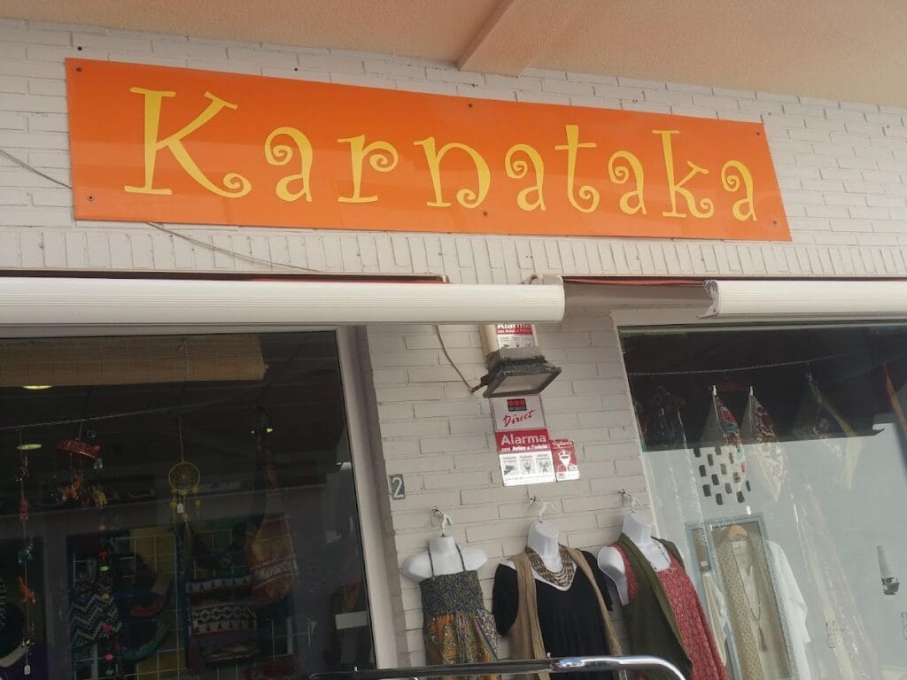 Fachada de la tienda Karnataka en La Manga del Mar Menor con llamativo rótulo naranja y expositores de ropa y complementos étnicos en el escaparate