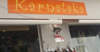 Fachada de la tienda Karnataka en La Manga del Mar Menor con llamativo rótulo naranja y expositores de ropa y complementos étnicos en el escaparate