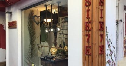 Escaparate de Sie7e con ropa, bolsos y accesorios bohemios bajo rótulo de madera y letras rojas en La Manga del Mar Menor