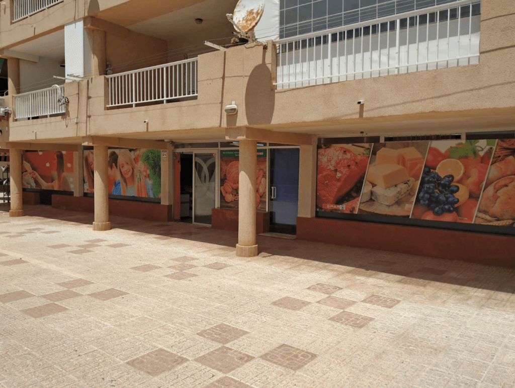 Fachada del Spar Express Puerto Bello en La Manga del Mar Menor con escaparates decorados con murales de frutas y productos frescos