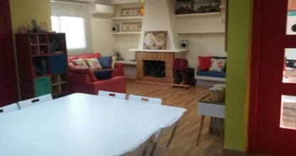 Sala de estar y comedor de apartamento Studioland con sofá rojo, chimenea y mesa blanca en La Manga del Mar Menor