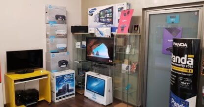 Interior de sunny-pc Computer Services con televisores, impresoras HP, iMac y productos informáticos expuestos