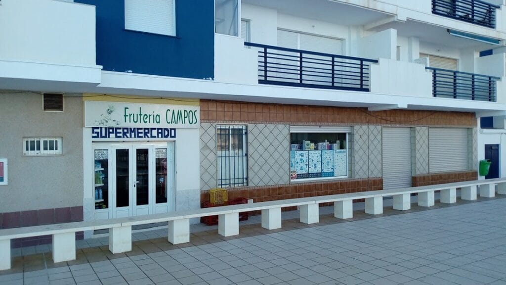 Fachada exterior de Supermercado Fruteria Campos en La Manga del Mar Menor, local de planta baja con rótulo verde y azul en edificio blanco