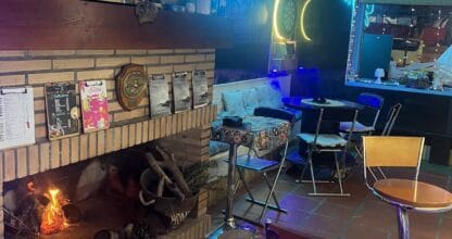 Interior acogedor de Taberna Siroco con chimenea encendida, letrero neón azul, mesas y decoración vintage en La Manga