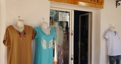 Fachada de la tienda Tangri moda y complementos con rótulo de madera y vestidos expuestos en exterior en La Manga del Mar Menor
