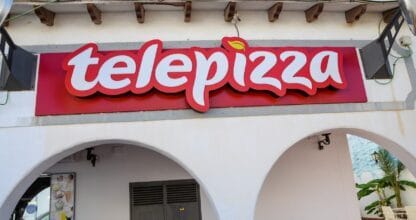 Rótulo luminoso rojo de Telepizza en La Manga del Mar Menor sobre fachada blanca con arcos de estilo mediterráneo