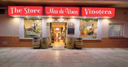 Fachada nocturna de The Store Mar de Vinos Vinoteca con barriles decorativos en la entrada, La Manga del Mar Menor