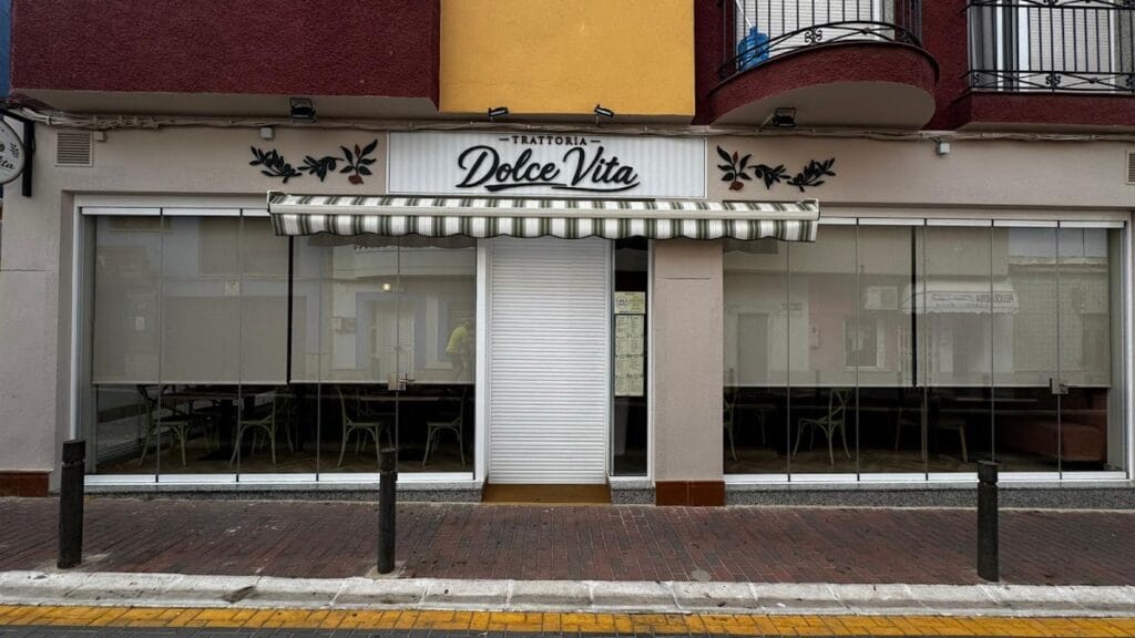 Fachada exterior de Trattoria Dolce Vita en La Manga del Mar Menor con toldo a rayas verdes y rótulo con decoración de olivo