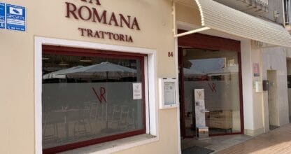 Fachada de Trattoria Via Romana en La Manga del Mar Menor con rótulo en rojo oscuro y escaparate con mesas interiores