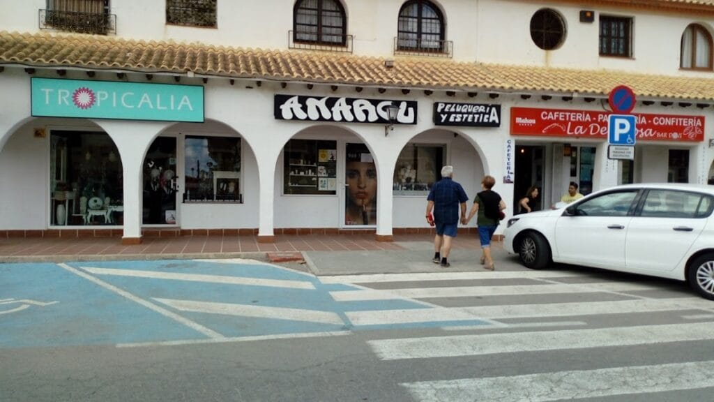 Fachada comercial en La Manga del Mar Menor con local Tropicalia junto a peluquería y cafetería en zona de arcos blancos