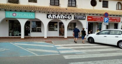 Fachada comercial en La Manga del Mar Menor con local Tropicalia junto a peluquería y cafetería en zona de arcos blancos