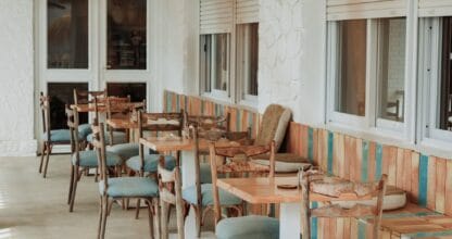 Interior luminoso del restaurante Ubuntu en La Manga del Mar Menor con sillas de ratán azul, mesas de madera y lámparas de mimbre colgantes