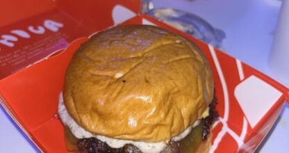 Hamburguesa artesanal con pan brioche, bacon y salsa en caja roja de Única Burger Las Dunas en La Manga del Mar Menor