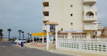 Edificio Urbanización Villa Morena en La Manga del Mar Menor con cafetería-heladería en planta baja y palmeras al fondo
