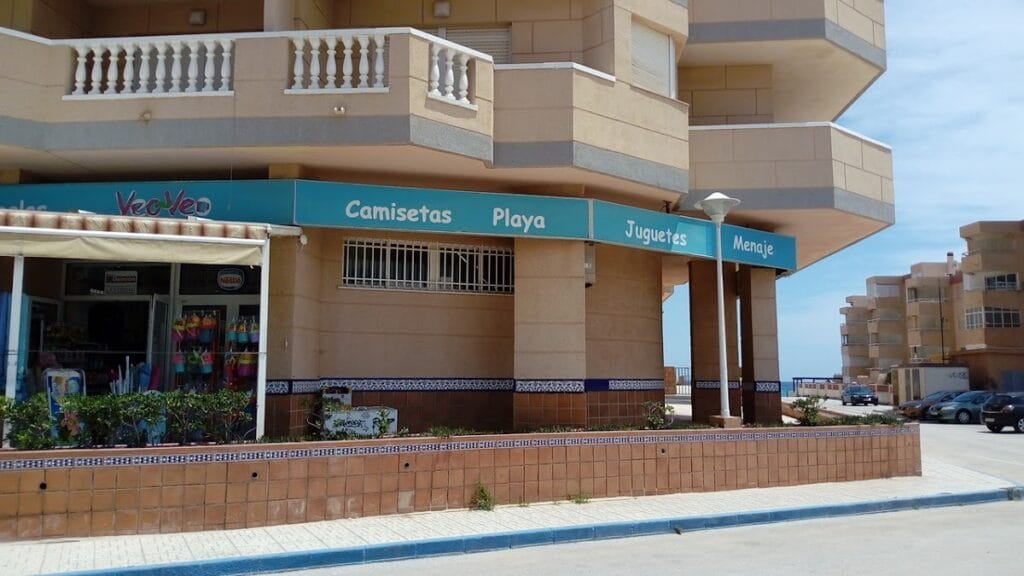 Fachada de Veo-Veo Castillo de Mar en La Manga del Mar Menor con toldo turquesa y oferta de camisetas, playa, juguetes y menaje