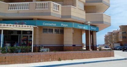 Fachada de Veo-Veo Castillo de Mar en La Manga del Mar Menor con toldo turquesa y oferta de camisetas, playa, juguetes y menaje