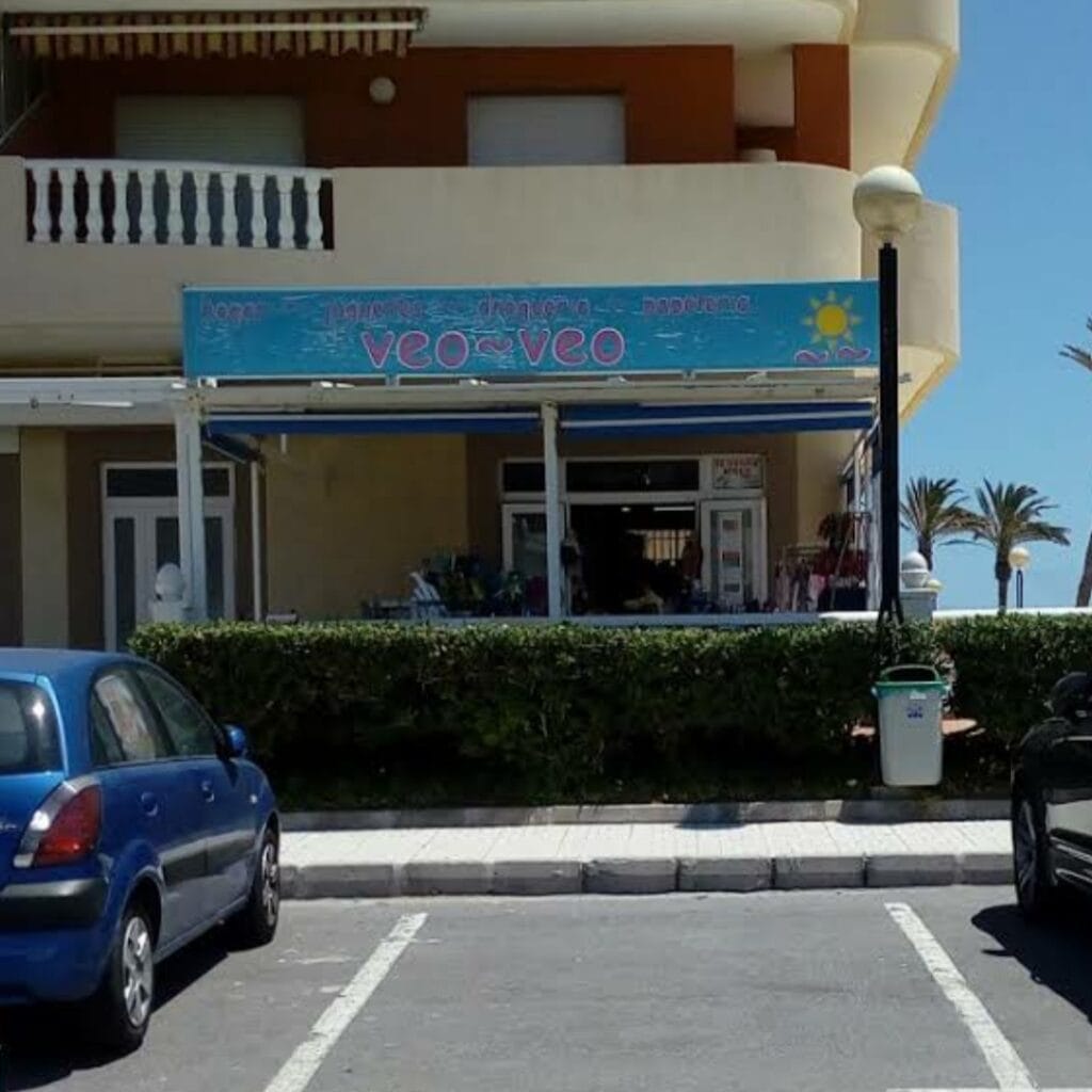 Fachada de Veo-Veo prensa y revistas en La Manga del Mar Menor con toldo azul y palmeras al fondo