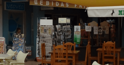 Terraza exterior de Veo~Veo Bohemia con mesas y sillas blancas bajo toldo amarillo en La Manga del Mar Menor