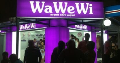 Puesto WaWeWi de yogurt iluminado en morado con clientes haciendo cola por la noche en La Manga del Mar Menor
