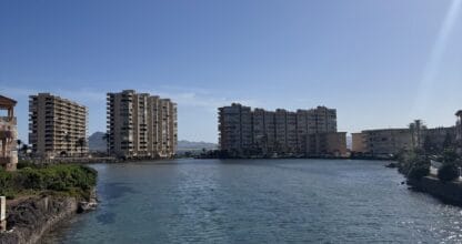 Canal de aguas turquesas del Wolf Bridge en La Manga del Mar Menor con edificios residenciales a ambas orillas bajo cielo despejado