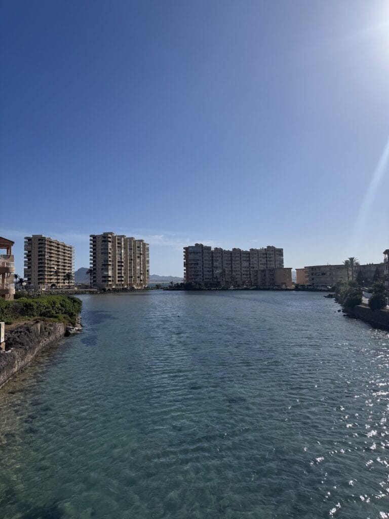 Canal de aguas turquesas del Wolf Bridge en La Manga del Mar Menor con edificios residenciales a ambas orillas bajo cielo despejado