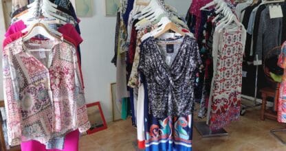 Interior de tienda de ropa con percheros de vestidos y blusas de colores en Yo Encuentro, La Manga del Mar Menor