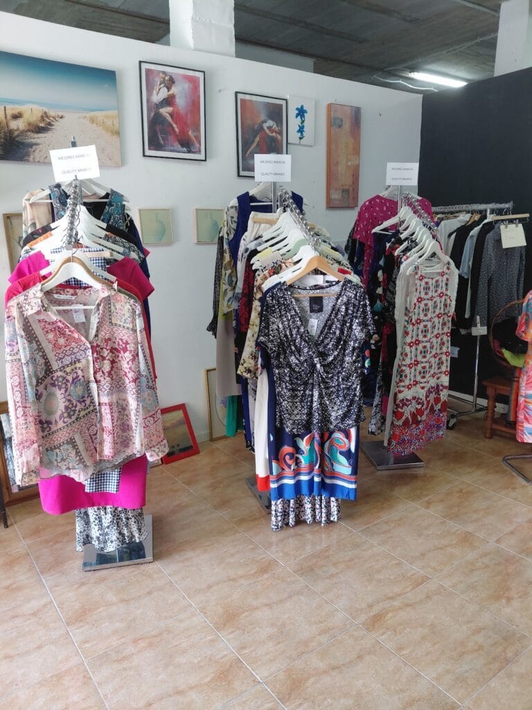 Interior de tienda de ropa con percheros de vestidos y blusas de colores en Yo Encuentro, La Manga del Mar Menor