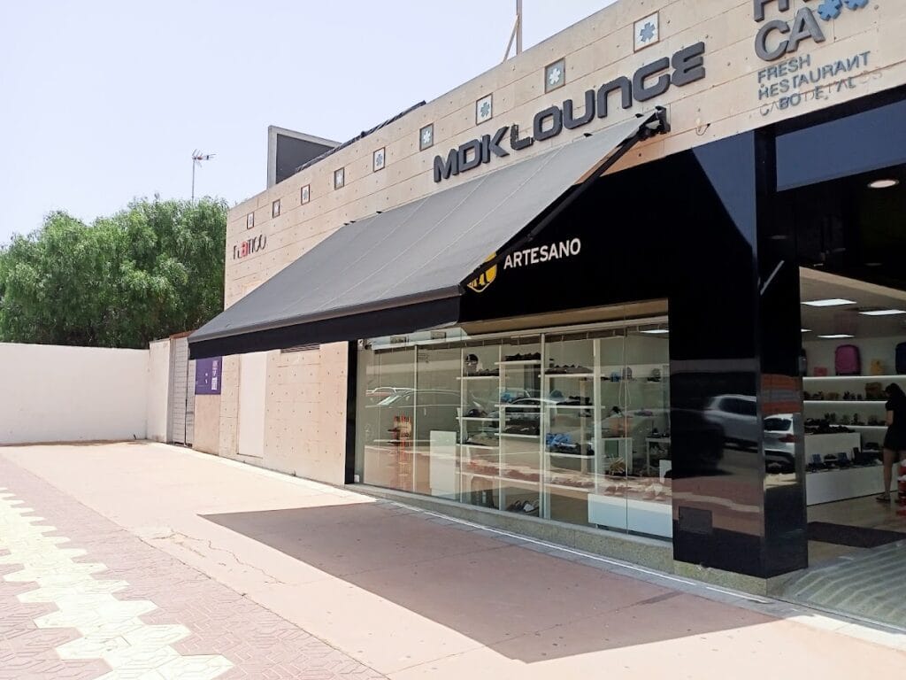 Fachada exterior de Zapaterías Salvador Artesano con amplio escaparate de calzado y toldo negro en Cabo de Palos