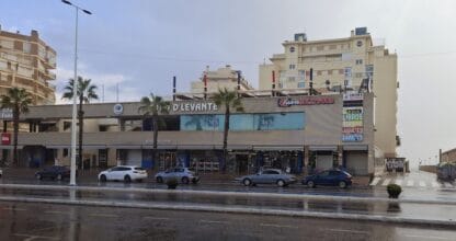 Fachada del centro comercial Zoco D'Levante con varios locales comerciales en día lluvioso, La Manga del Mar Menor